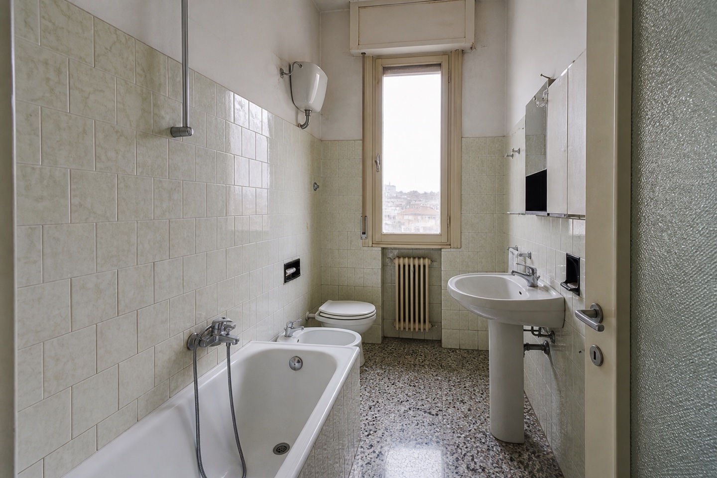Bagno prima della ristrutturazione, con rivestimenti e sanitari datati